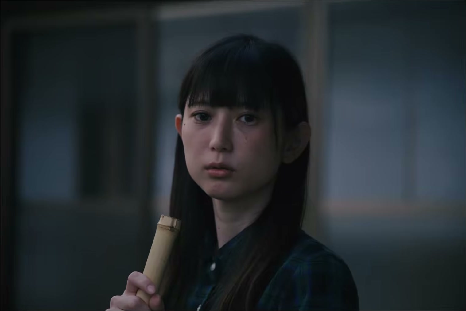 室内で竹の筒を手に、相手を見つめる女性。